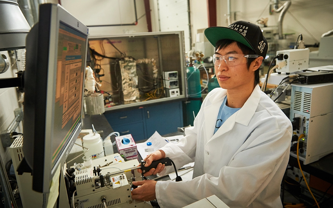 Male Asian engineering student working on computer in lab.