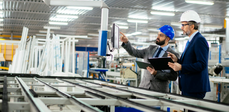 Two men in manufacturing facility surrounded by equipment.