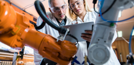Male and female working in manufacturing facility. Machines in the foreground.