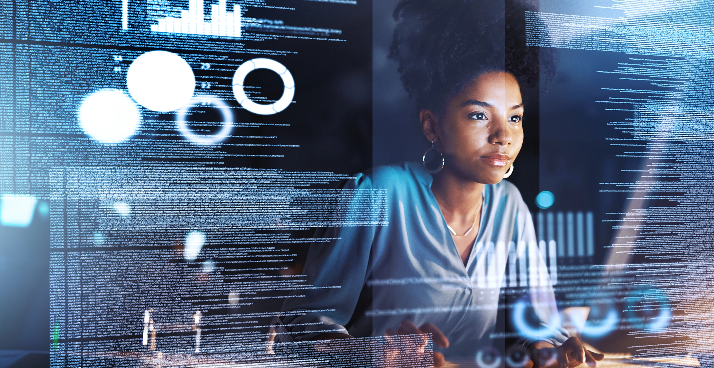 Close up of woman of color working on computer with a data layer superimposed in foreground.