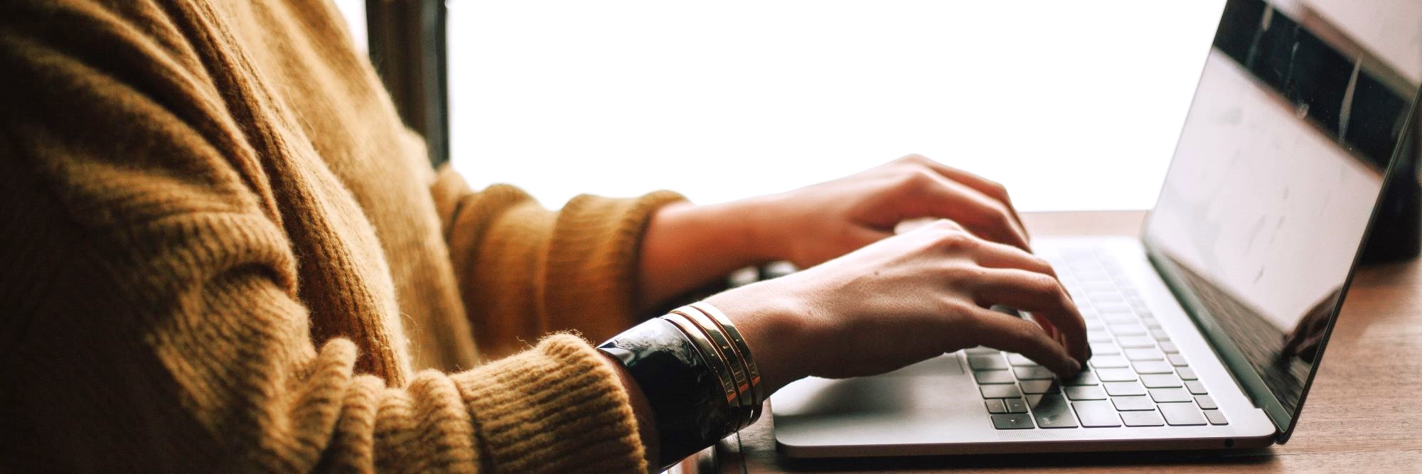 Close up of hands typing on keyboard of a laptop.