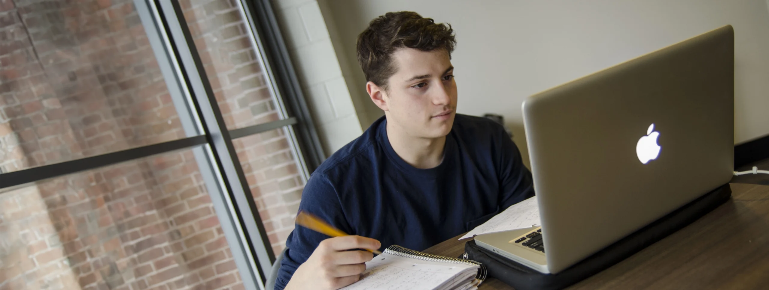 UConn student studying at table in front of laptop.
