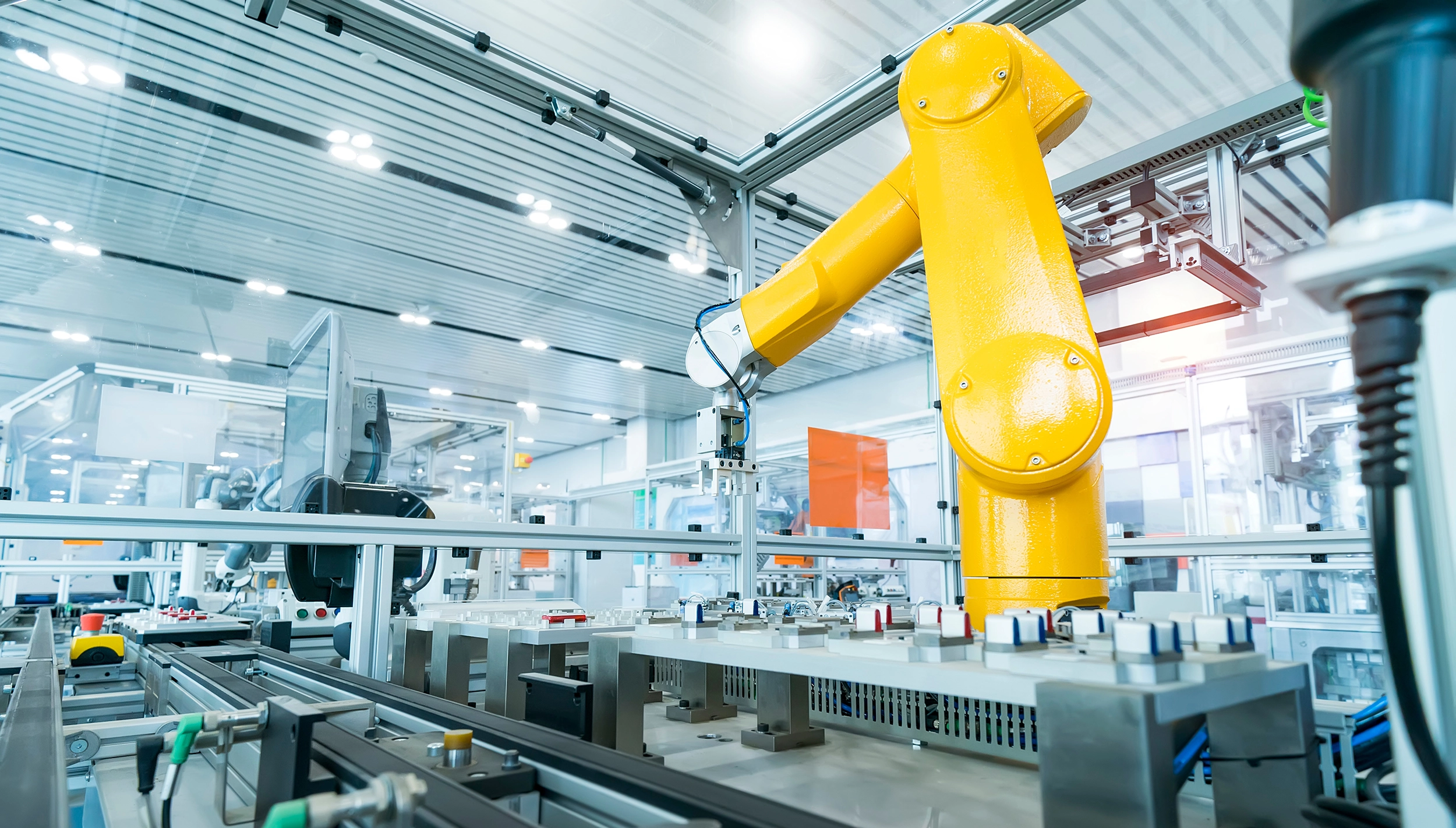 Manufacturing facility, large yellow robotics arm and assemble line component conveyer.