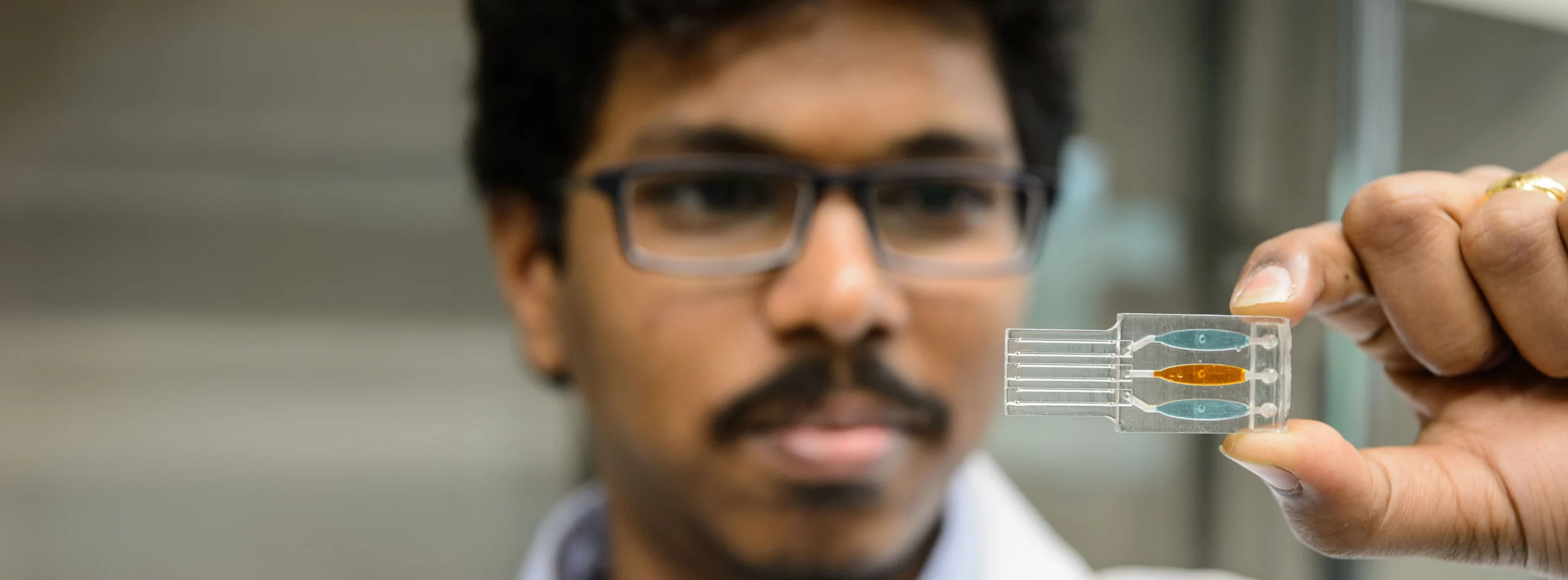 Close up of male of color holding a computer chip and looking at it.
