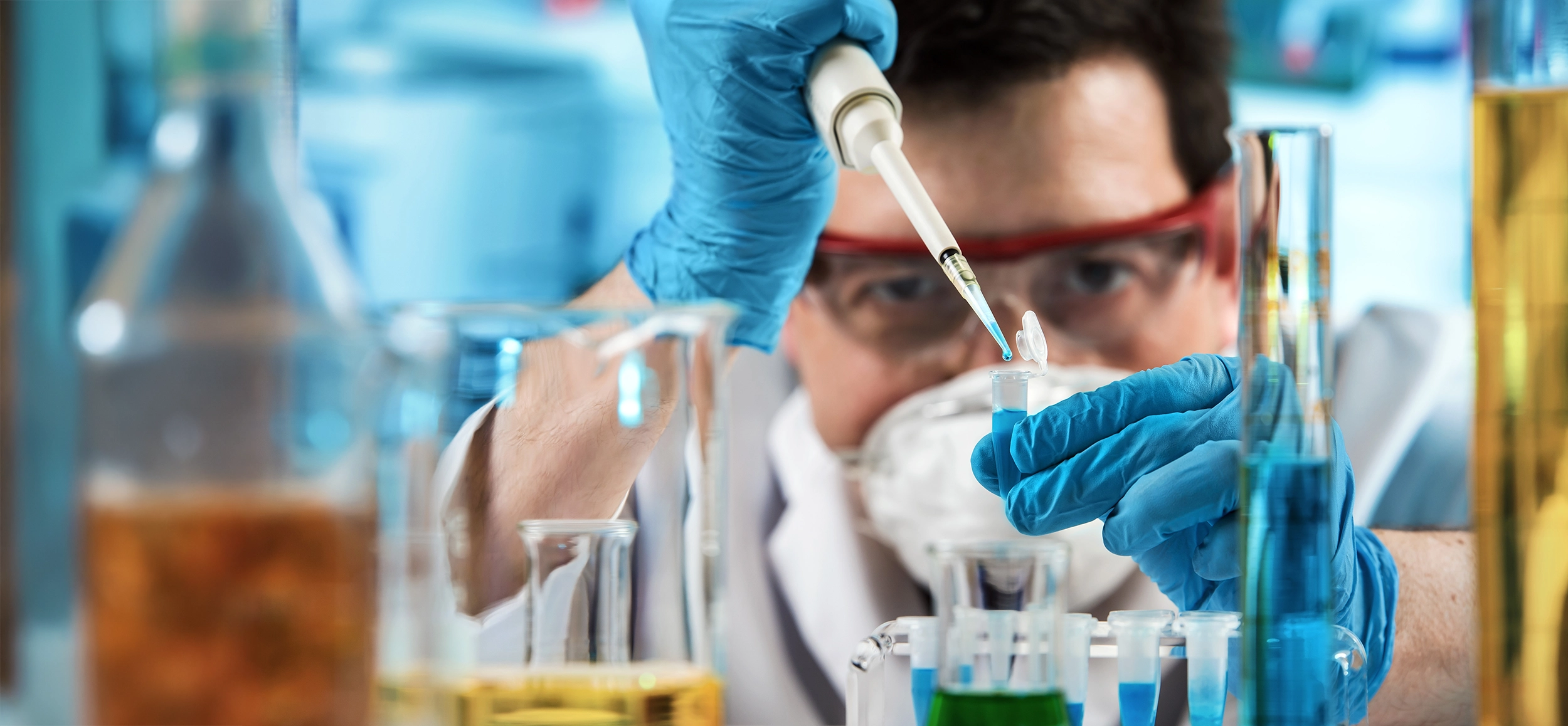 Close up of Engineering research with wearing blue gloves holding a pipette and test tube.