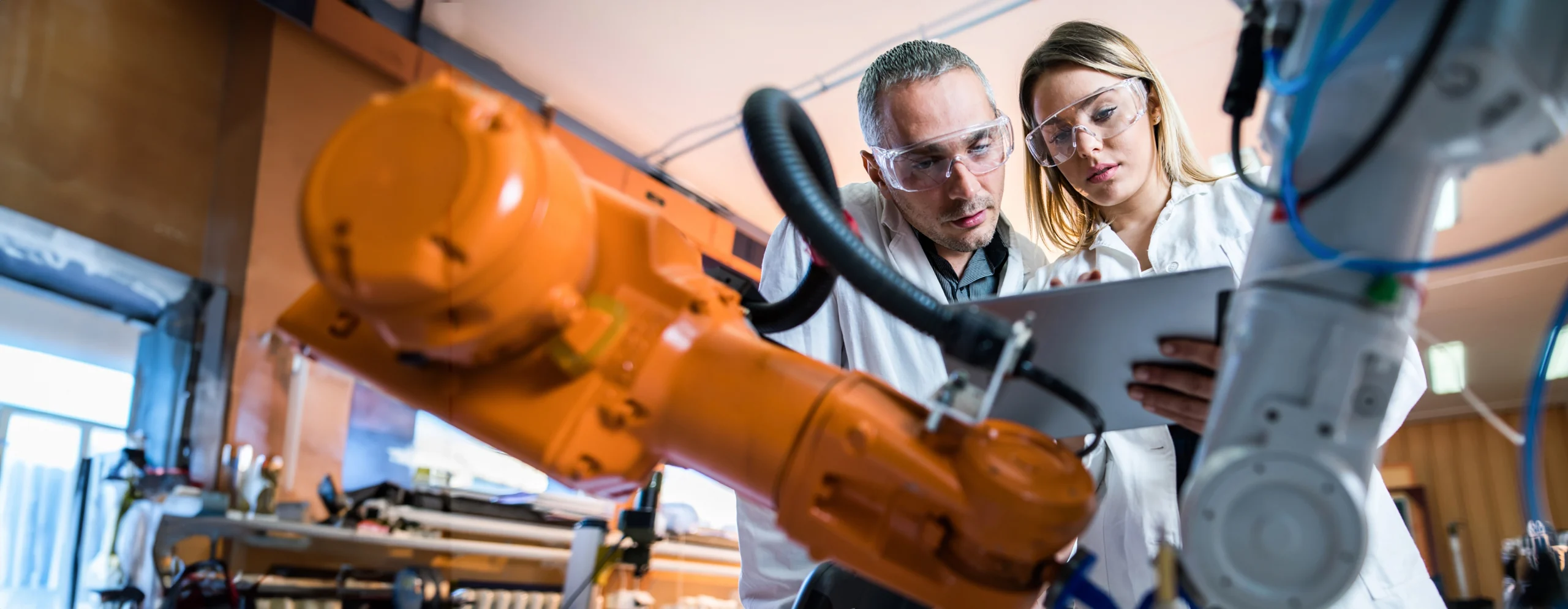 Male and female examining data with manufacturing machinery n foreground.