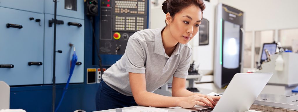 Asian female engineer looking working on laptop in scientific lab.